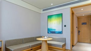Un área de espera moderna con un sofá gris, una mesa de madera con una bandeja y un cuadro abstracto grande en la pared.