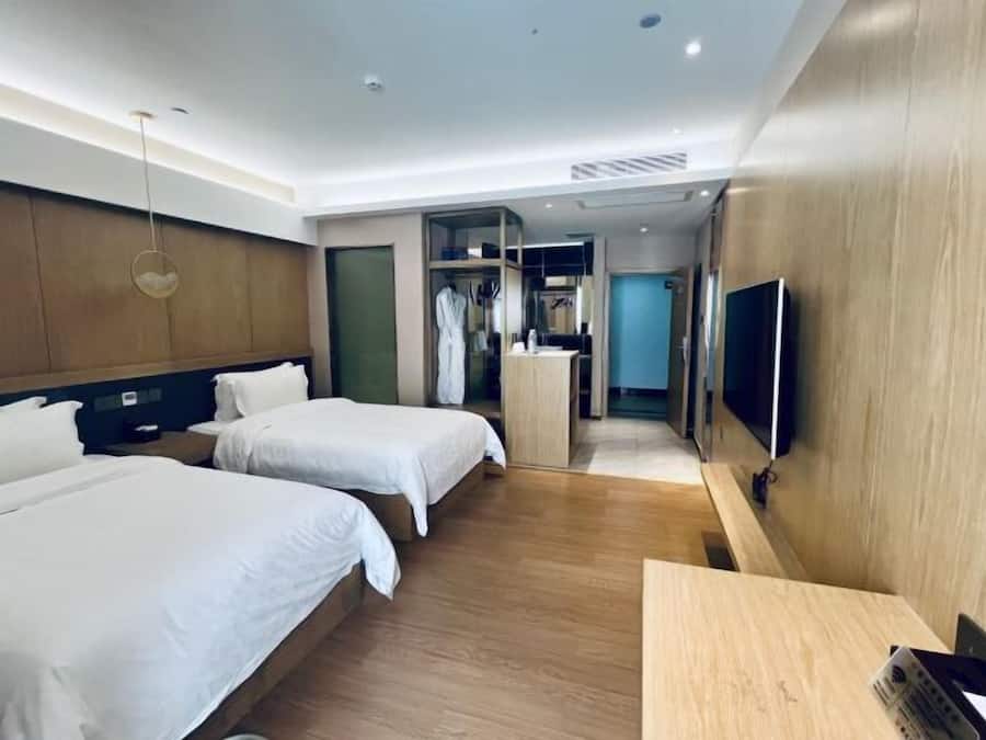 Habitación de hotel con dos camas, un televisor, un escritorio de madera y un vestidor.