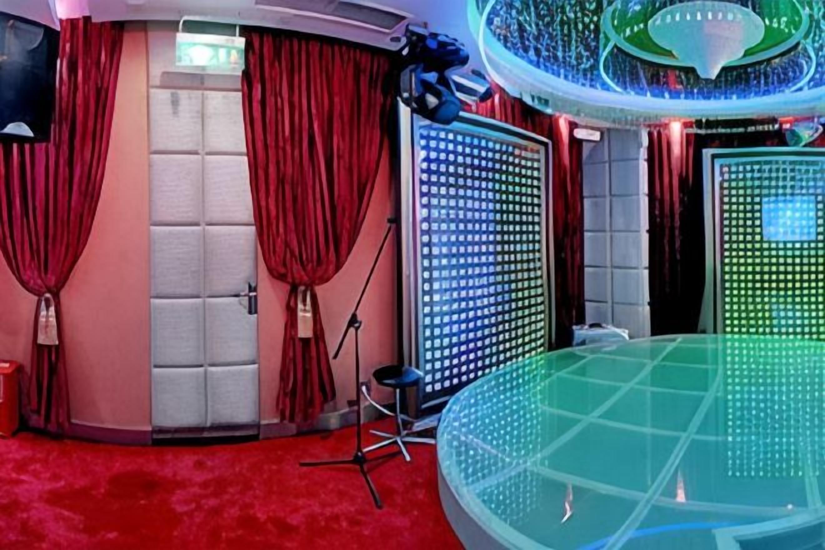 A room with a red carpet, a large circular table, and a wall with a grid of lights.