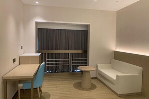 A modern room with a wooden desk, a blue chair, a white sofa, and a small round table. - Shenzhen Ruili Hotel (Window of the World Baishizhou Subway Station) (Shenzhen)