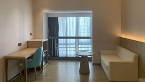 A modern room with a desk, chair, round table, and sofa. - Shenzhen Ruili Hotel (Window of the World Baishizhou Subway Station) (Shenzhen)