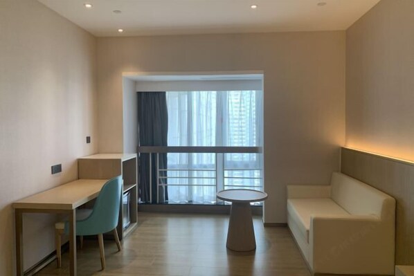 A modern room with a desk, chair, round table, and sofa. - Shenzhen Ruili Hotel (Window of the World Baishizhou Subway Station) (Shenzhen)