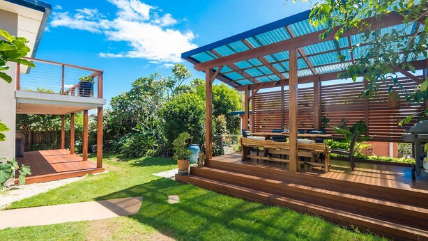 A modern outdoor patio with wooden furniture and a covered seating area. - Beach Views - Spacious home by the ocean (Lennox Head)
