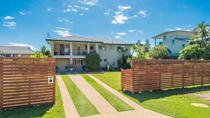 A two-story house with a paved driveway, a well-maintained lawn, and a wooden fence. - Beach Views - Spacious home by the ocean (Lennox Head)