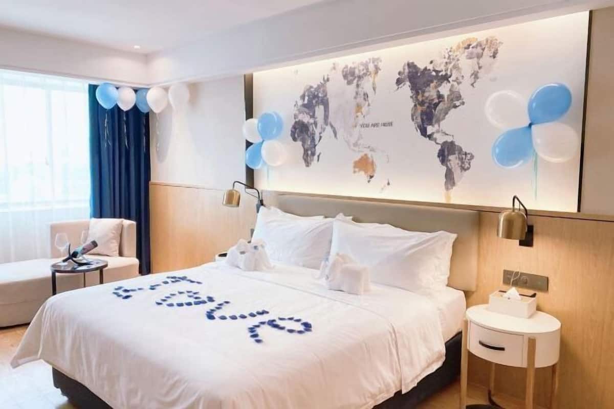 Ein Hotelzimmer mit Bett, Nachttisch, Stuhl und einer Weltkarte an der Wand.