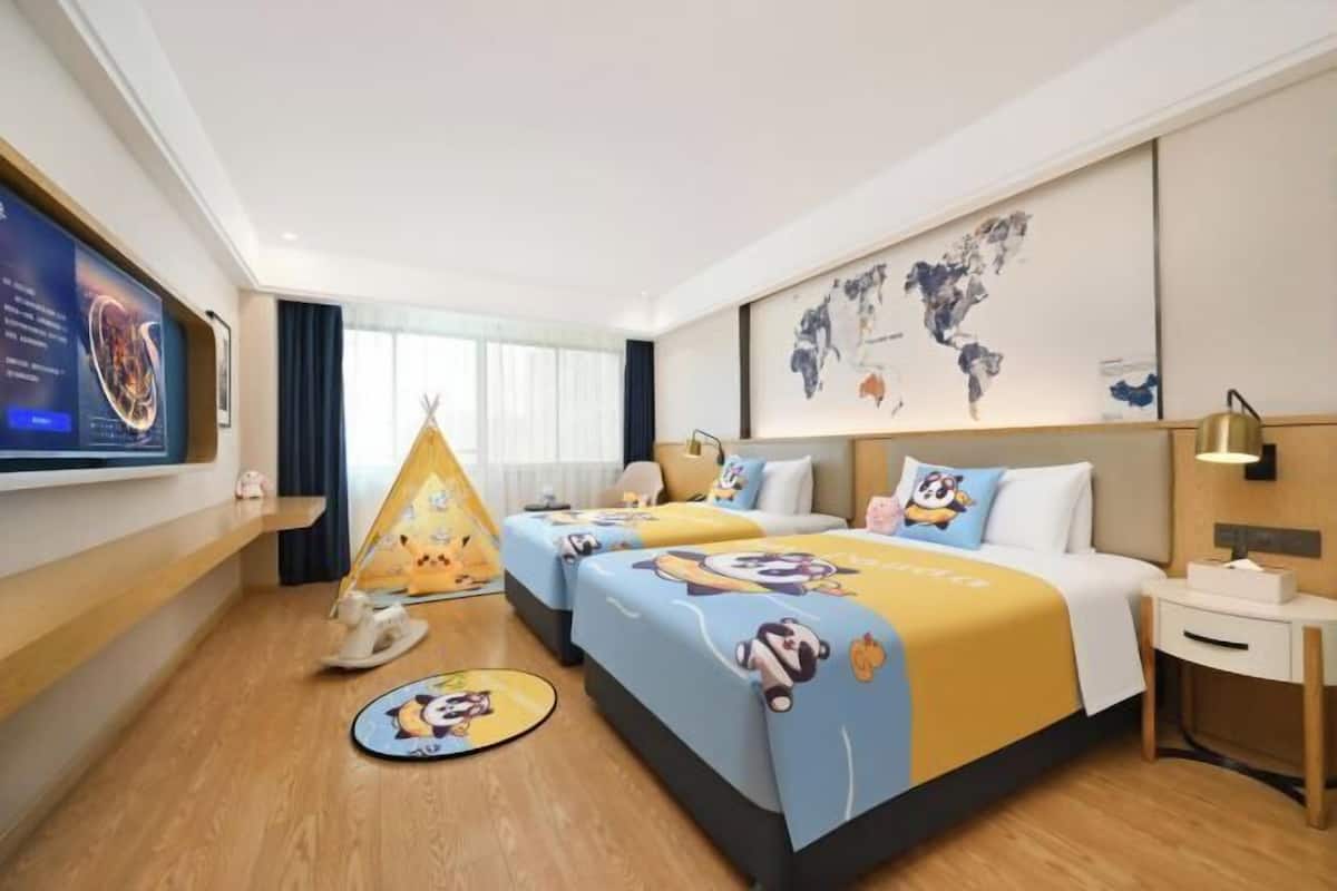 Ein Hotelzimmer mit zwei Betten, einem Fernseher, einer Weltkarte, einem Schreibtisch und einem kleinen Tisch mit Teekanne.