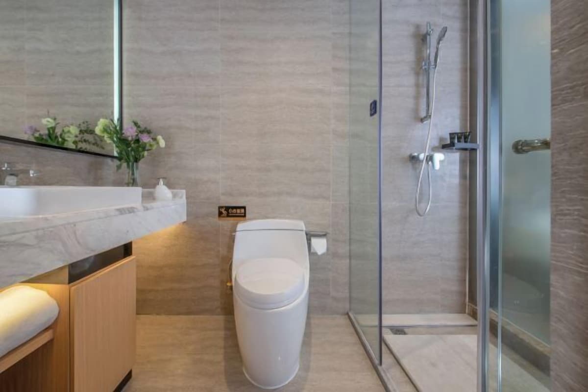 A modern bathroom with a glass shower enclosure, a toilet, and a vanity with a mirror.