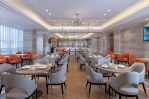 A spacious dining area with multiple tables and chairs, a central bar, and a modern ceiling design.