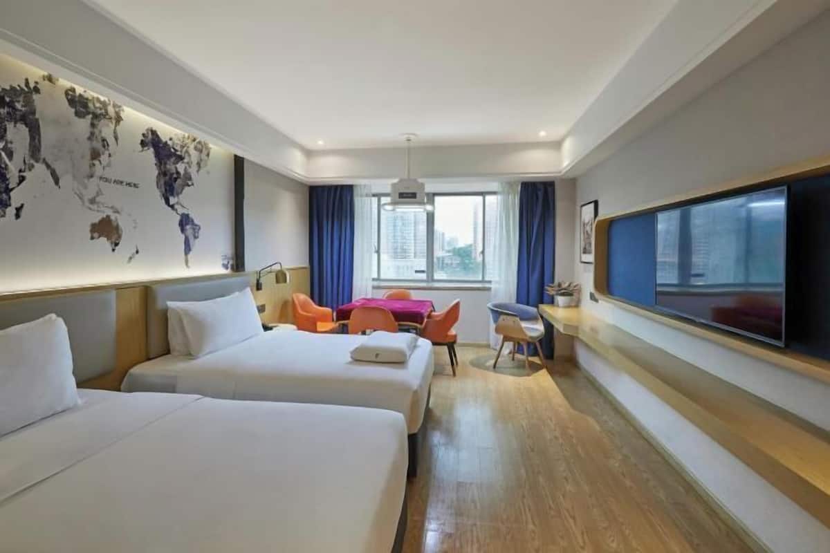 Ein Hotelzimmer mit zwei Betten, einem Schreibtisch, einem Stuhl, einem Fernseher und einer Weltkarte an der Wand.
