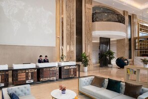 A hotel lobby with a reception desk, seating area, and a large world map projection. - Kyriad Marvelous Hotel (Shenzhen Longhua Guanlan Zhucun Subway Station) (Shenzhen)