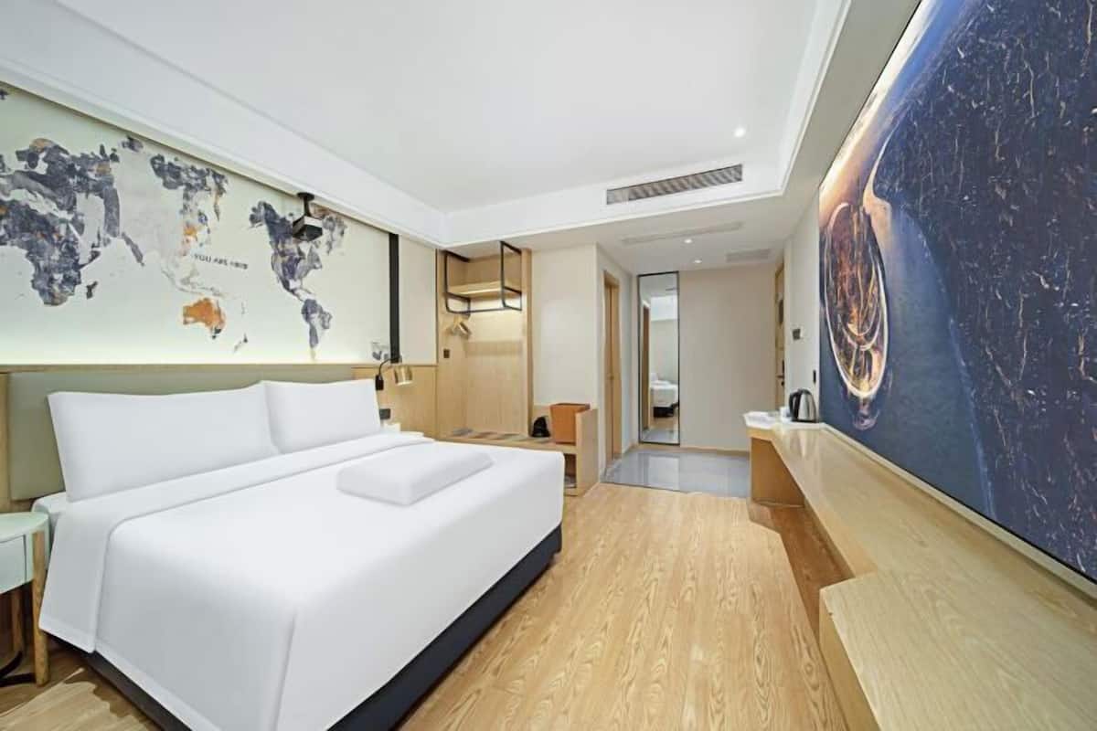 Ein modernes Hotelzimmer mit einem großen Bett, einer Weltkarte an der Wand und einem großformatigen Kunstwerk.