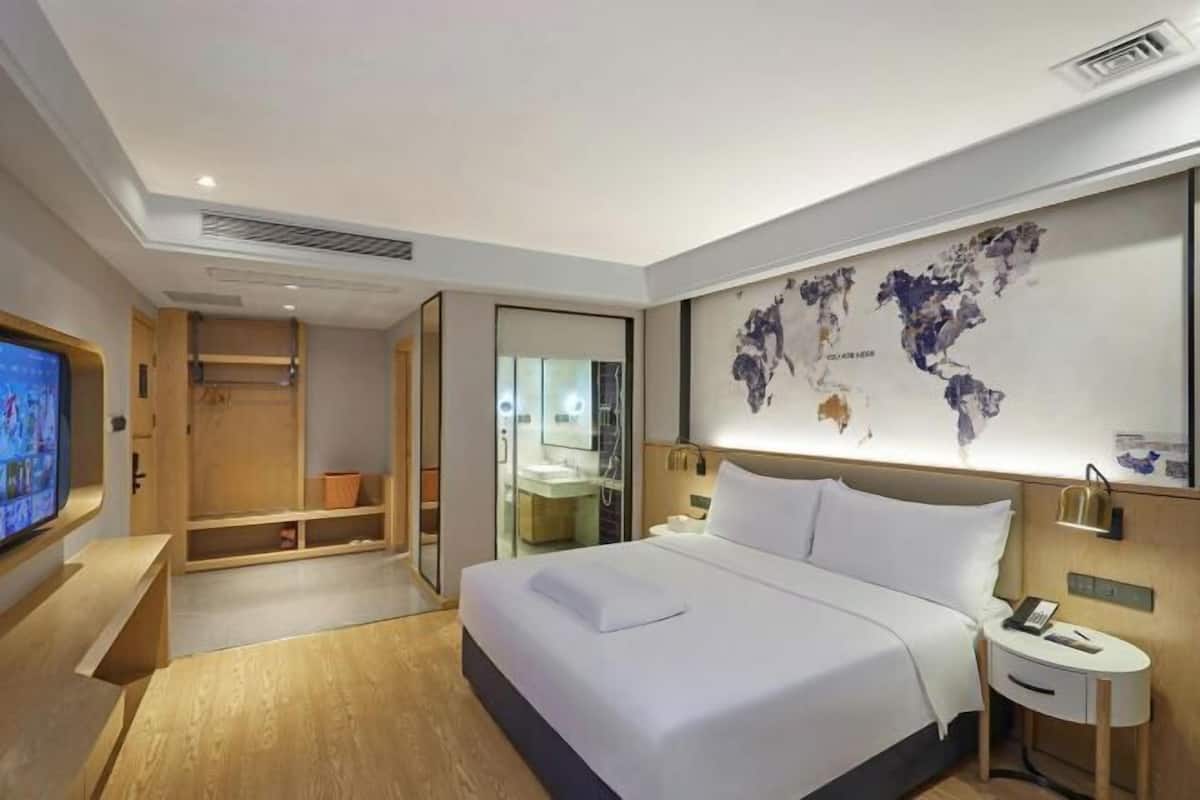 Ein modernes Hotelzimmer mit einem großen Bett, einem Fernseher, einer Karte an der Wand und einem begehbaren Kleiderschrank.