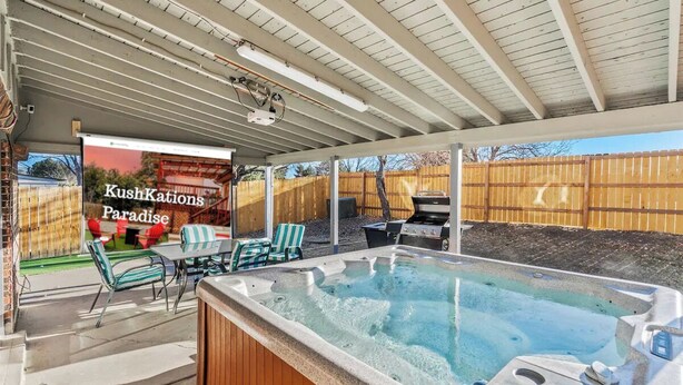 Ein Außenbereich mit Whirlpool, überdachter Terrasse, Sitzgelegenheit und Grill.