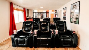 Ein Heimkino mit schwarzen Ledersesseln, einem Popcorneimer und einer Coca-Cola-Flasche.
