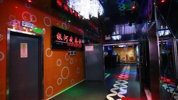 A corridor with patterned walls, a neon sign, and a floor with circular designs.