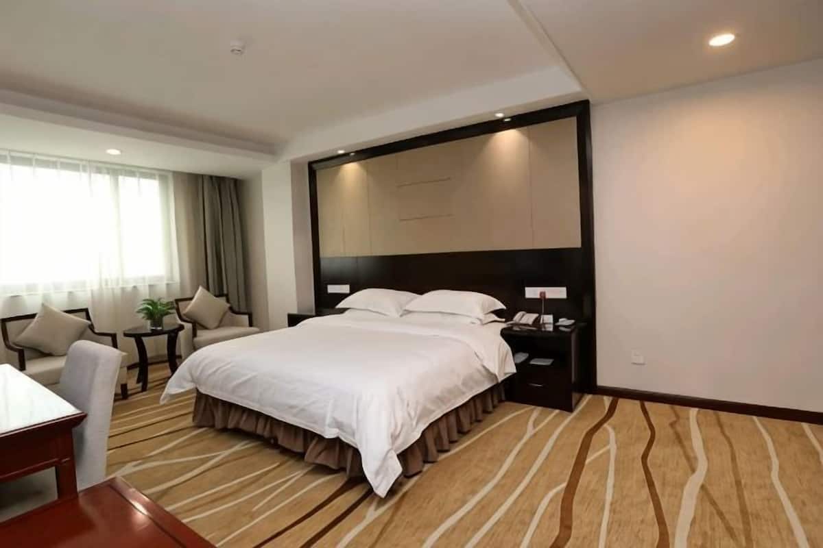 Een hotelkamer met een groot bed, nachtkastjes, een bureau en een stoel.