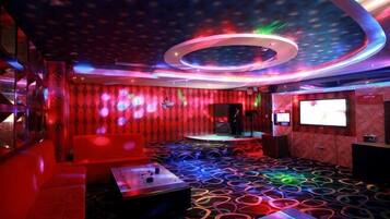 A room with a circular ceiling light, a stage, and a large screen.