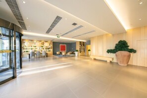 A spacious lobby with a reception desk, seating area, and a large potted plant. - Ji Hotel (Beijing)