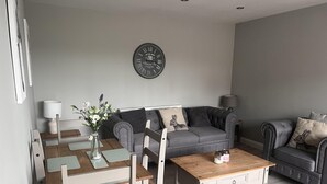 Un salon moderne avec un canapé gris, une table basse en bois et une table à manger avec des chaises.
