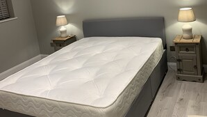 Une chambre moderne avec un grand lit, deux tables de chevet avec des lampes et un éclairage encastré au plafond.