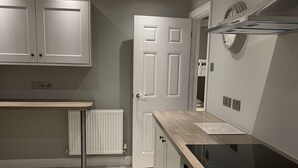 Une cuisine moderne avec des armoires blanches, un plan de travail en bois, une plaque de cuisson à induction et un four encastré.