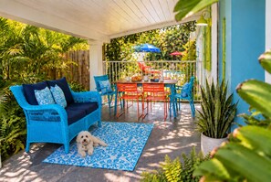 A covered patio area with a blue patterned rug, a white ceiling, and a dining table with chairs.