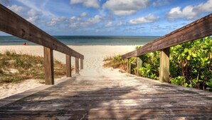A wooden boardwalk leading to a beach with a clear sky. - Lush, Secluded Pool + 5 Mins to Beach (Naples)