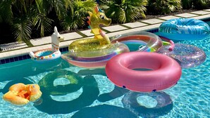 A swimming pool with various inflatable rings and a unicorn float. - Lush, Secluded Pool + 5 Mins to Beach (Naples)
