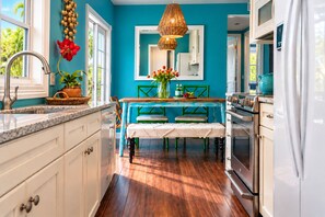 A kitchen with teal walls, a wooden dining table, and a white refrigerator.