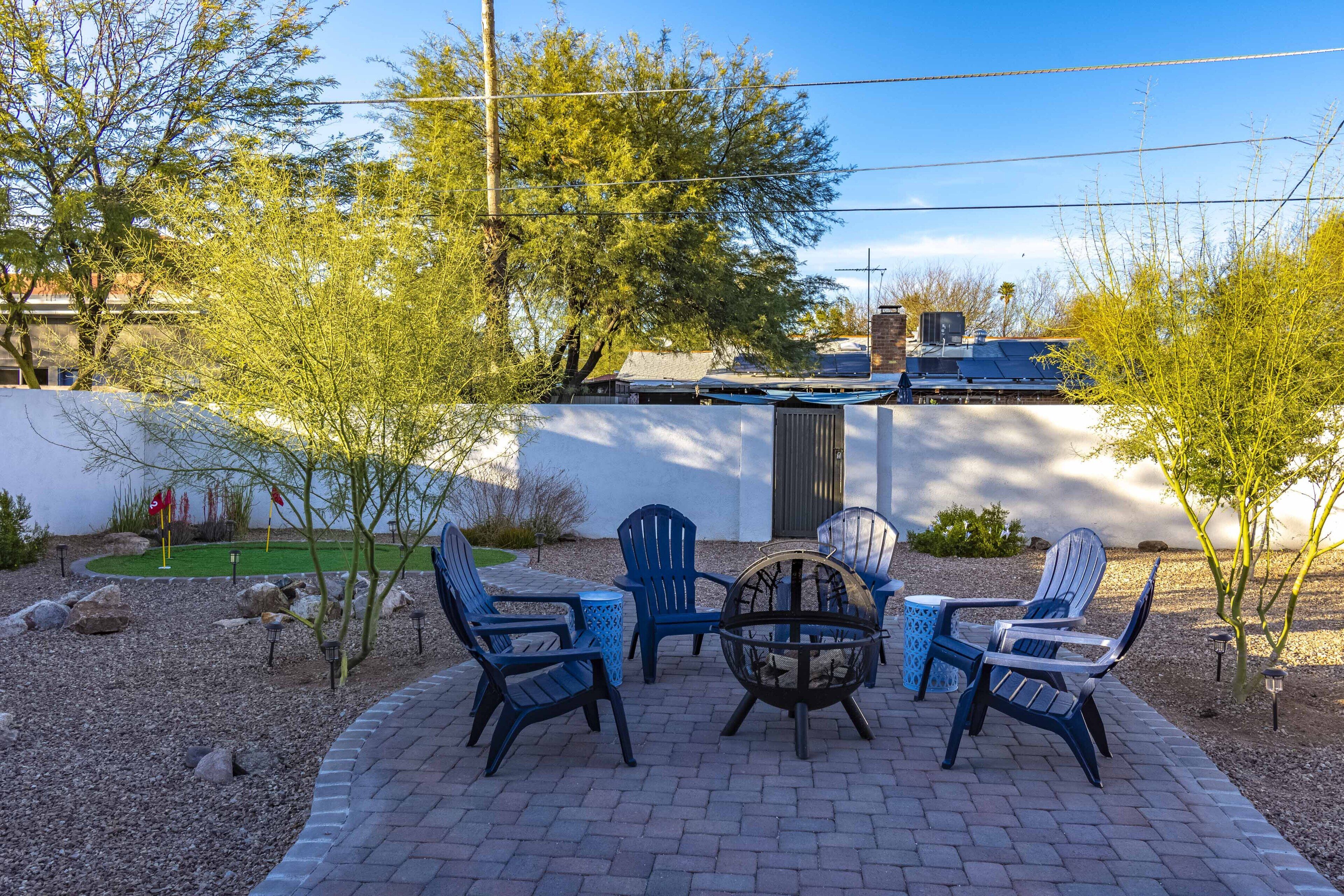 Une terrasse avec quatre fauteuils Adirondack, une table ronde et un foyer extérieur.