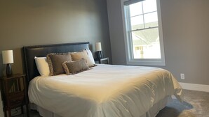 A bedroom with a bed, a ceiling fan, a window, and a nightstand with a lamp. - North Lincoln, Minutes from Pinnacle Bank Arena and Memorial Stadium (Lincoln)