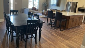 A spacious kitchen with a large island, wooden cabinets, and a dining area with a table and chairs. - North Lincoln, Minutes from Pinnacle Bank Arena and Memorial Stadium (Lincoln)