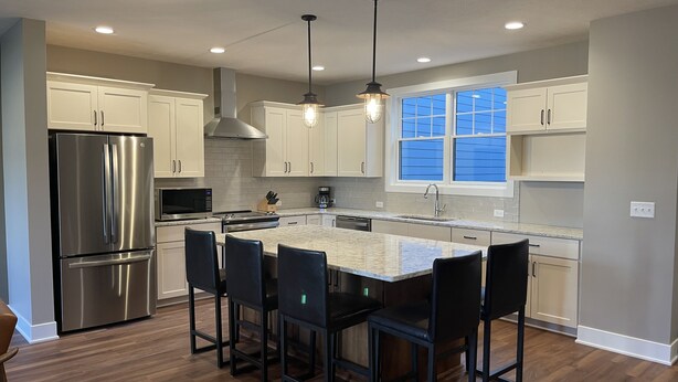 A modern kitchen with a central island, stainless steel appliances, and a large window. - North Lincoln, Minutes from Pinnacle Bank Arena and Memorial Stadium (Lincoln)
