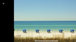 Une plage avec cinq parasols bleus alignés en rangée.