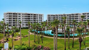 Un hôtel à plusieurs étages, doté de piscines extérieures et bordé de palmiers.