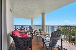 Enjoy ocean views from this balcony with a wicker chair, metal chair, and table.