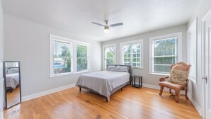 A bedroom with a bed, a chair, a ceiling fan, and large windows. - Highland villa near downtown and military base. (San Antonio)