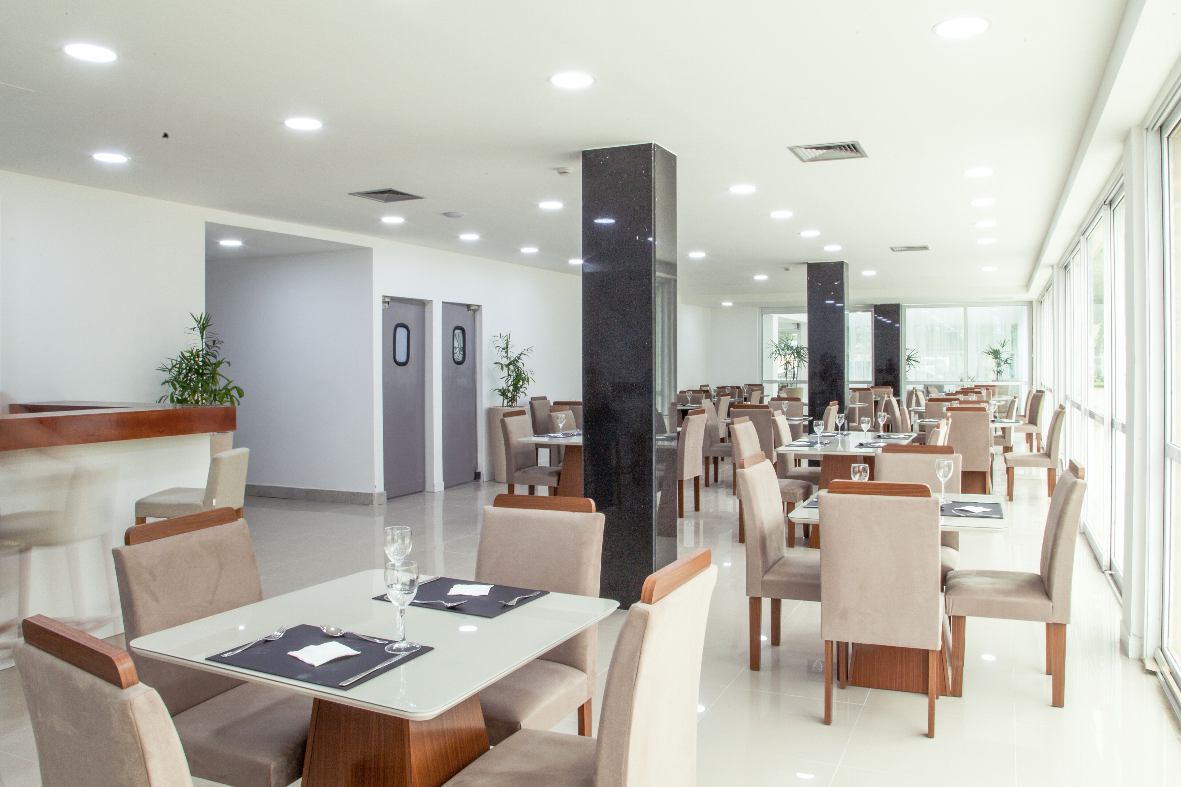 A spacious dining area with multiple tables and chairs, a reception desk, and a modern interior design.