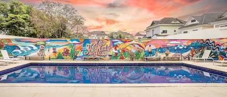 Una piscina al aire libre, sombrillas, sillones reclinables de piscina