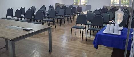 A conference room with rows of chairs, a long table, and a water dispenser on a table.