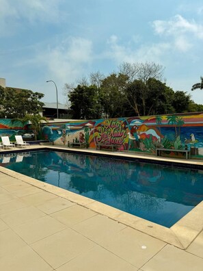 Una piscina al aire libre, sombrillas, sillones reclinables de piscina