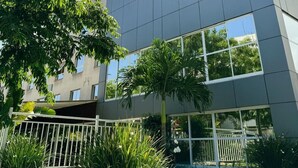 L’extérieur de l’hôtel Americana Townhouse présente un design moderne, de grandes fenêtres et un jardin bien entretenu.