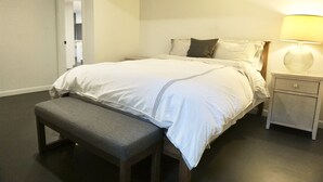 Ein Schlafzimmer mit Bett, Nachttisch, Lampe und Bank.