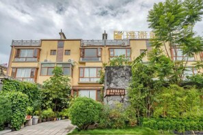A multi-story hotel with a garden in the foreground. - Pupeng Boutique Hotel (Yangbi)