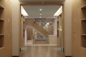 A hallway with wooden cabinets, a staircase, and a green sign on the floor. - Pupeng Boutique Hotel (Yangbi)