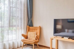 A room with a wooden chair, a television on a wooden stand, and sheer curtains. - Pupeng Boutique Hotel (Yangbi)