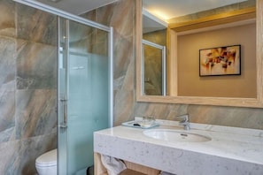 A bathroom with a glass shower enclosure, a white sink, and a marble-tiled wall. - Pupeng Boutique Hotel (Yangbi)