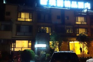 Un edificio de varios pisos con ventanas iluminadas y un letrero sobre la entrada.