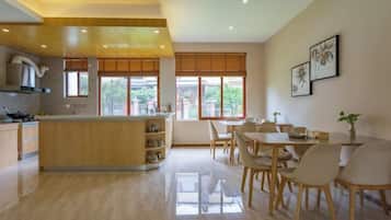 Una cocina amplia con una isla central, comedor con sillas y ventanas grandes.