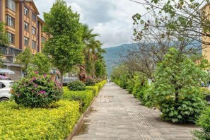 A paved pathway lined with greenery and buildings, leading towards a mountainous backdrop. - Pupeng Boutique Hotel (Yangbi)
